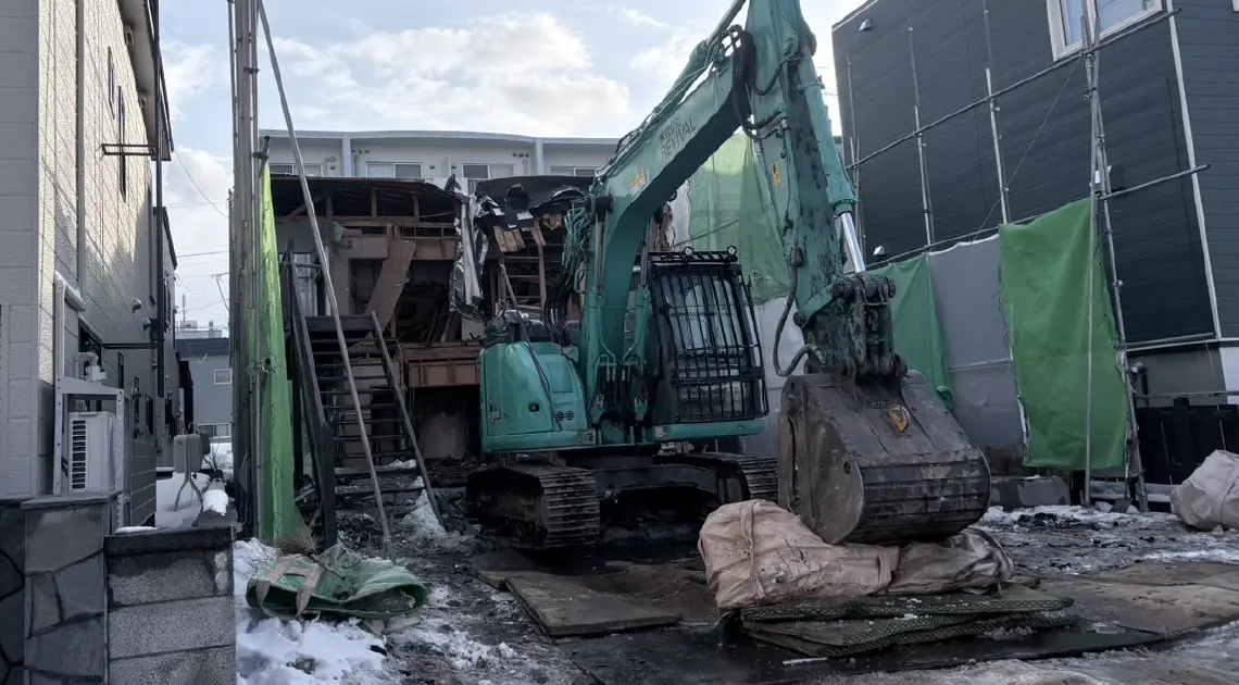 建物を解体中の緑色の重機